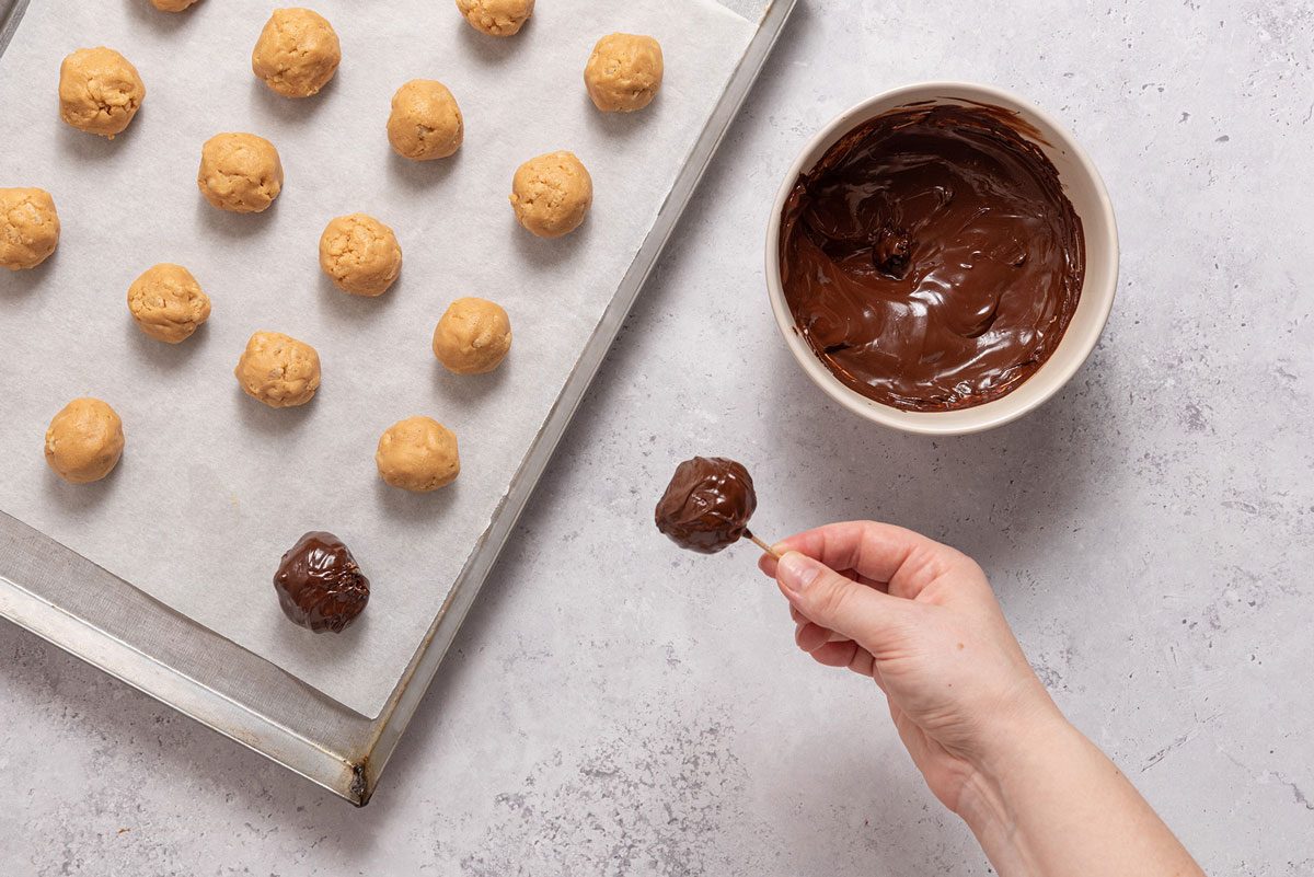 Dipping rice crispies peanut butter balls in chocolate