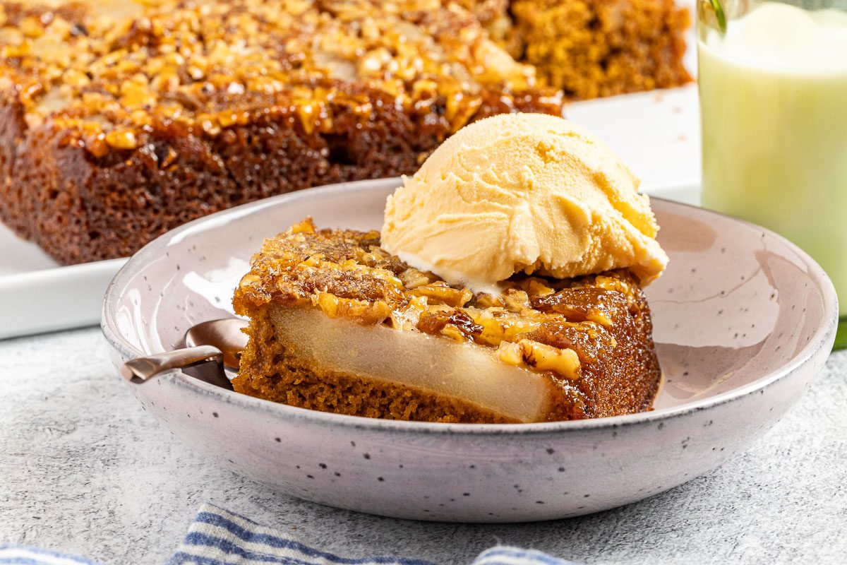 Taste of Home Pear Upside Down Cake recipe photo of the finished cake cute into a slice and topped with ice cream.