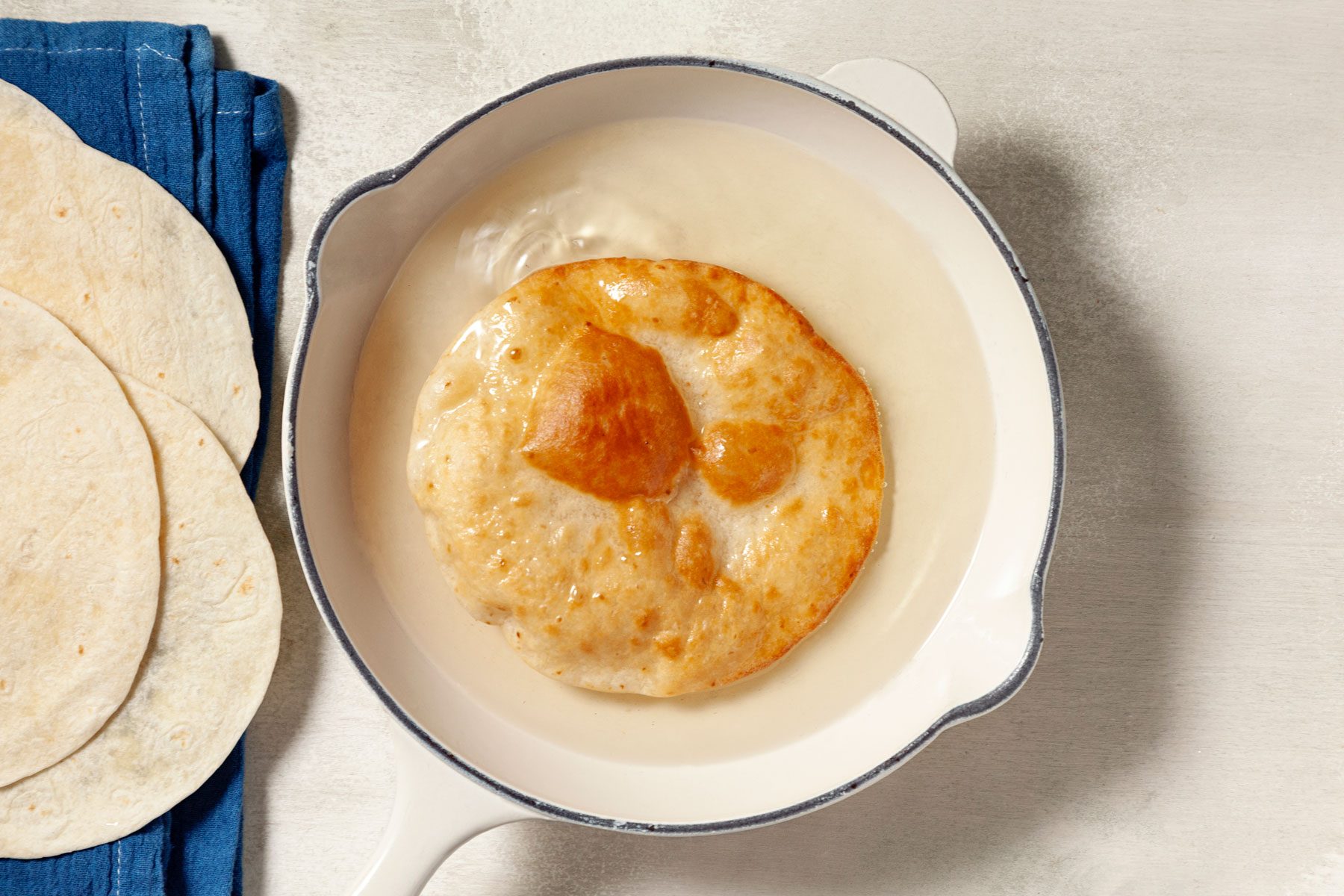 Tortilla being heated in a skillet.