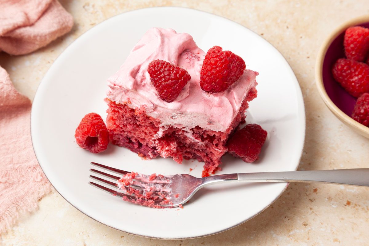 Once slice of Taste of Home Raspberry Cake garnished with fresh raspberries, pink linen