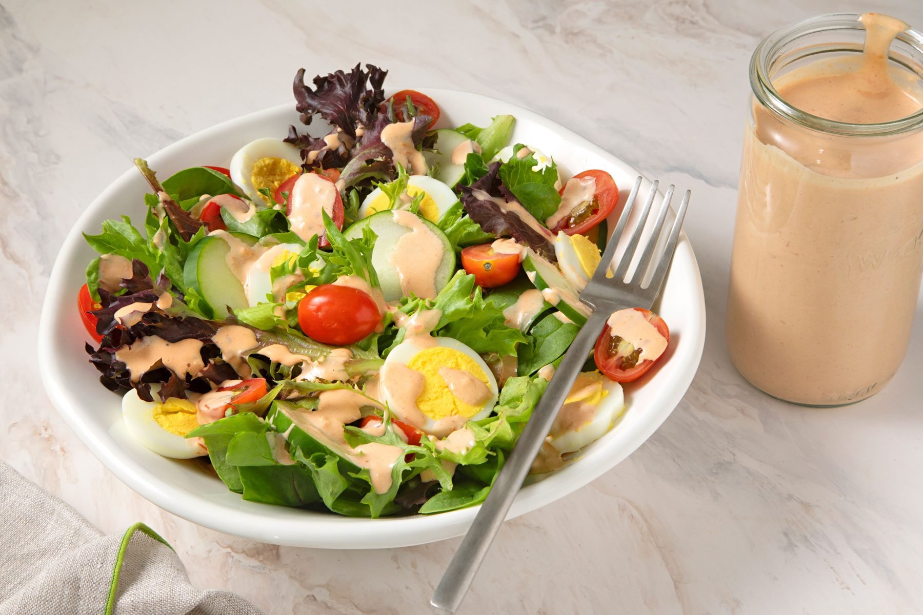 Russian Dressing next to a large bowl containing salad.