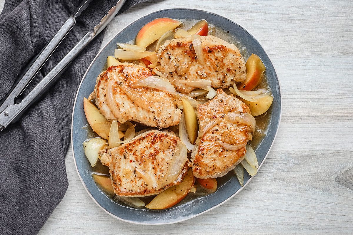 Skillet pork chops with apples and onion on a platter, cooked and ready to eat.