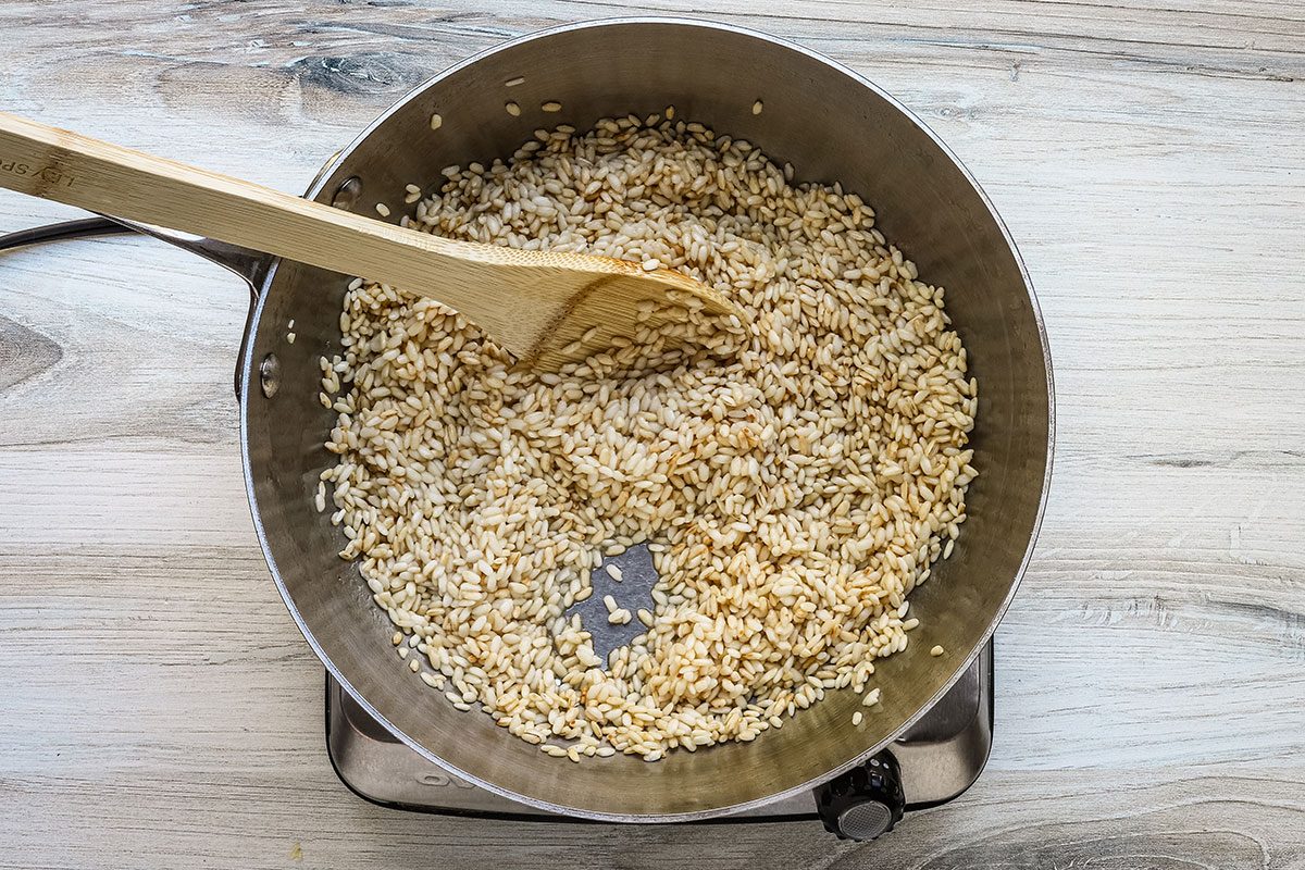 Risotto preparation with arborio rice lightly browned in a saucepan .