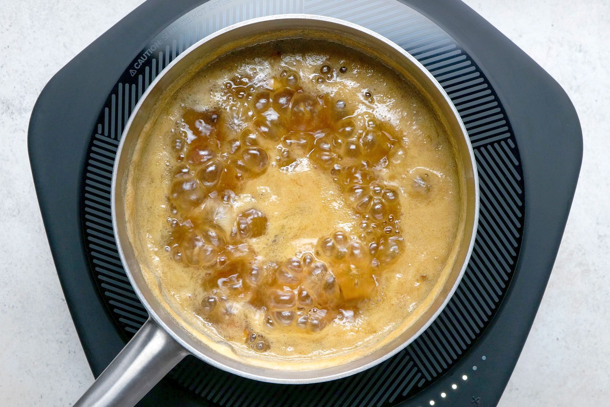 Overhead shot of a small saucepan; combine dates and water; bring to a boil; induction; marble surface;