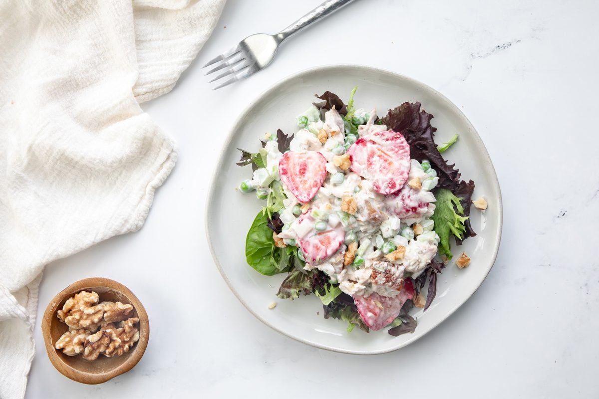 Overhead beauty shot for Taste of Home Tarragon Chicken Salad on a marble surface with forks, walnuts, and linen.