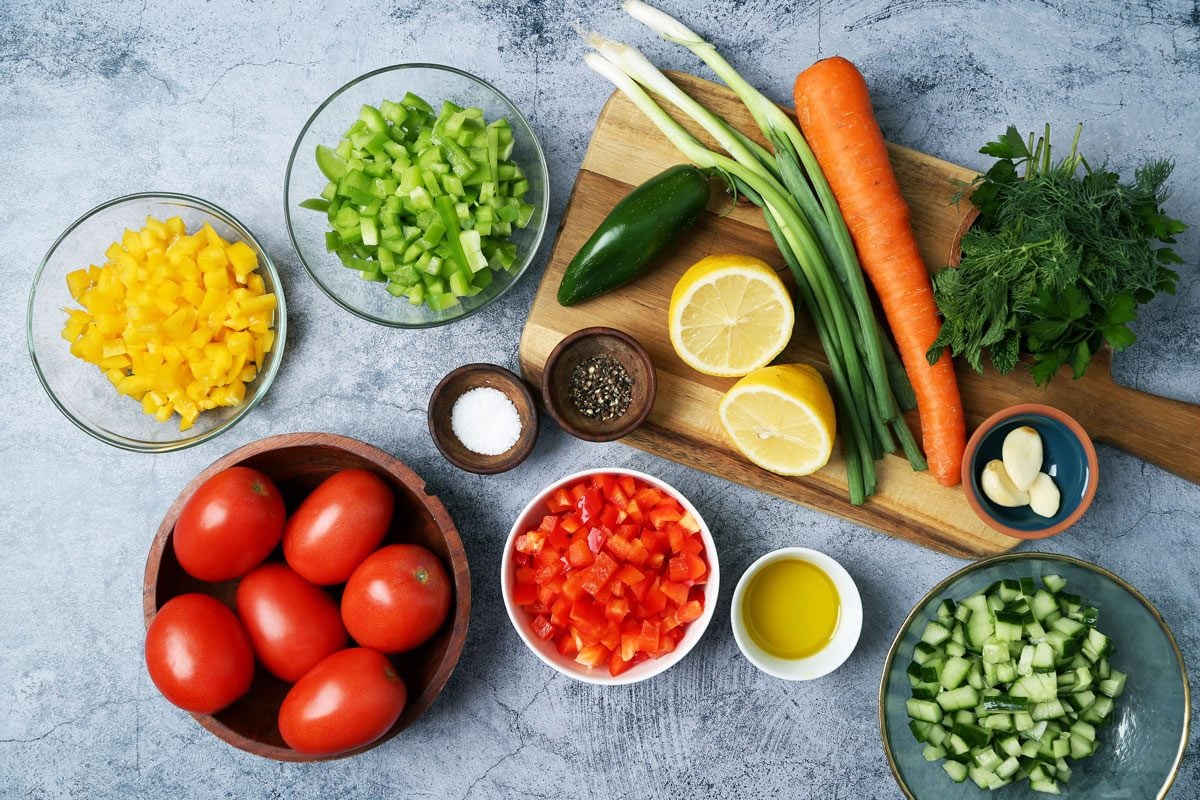 Ingredients for Taste of Home's Israeli Salad in small dishes with a wooden board on a blue surface