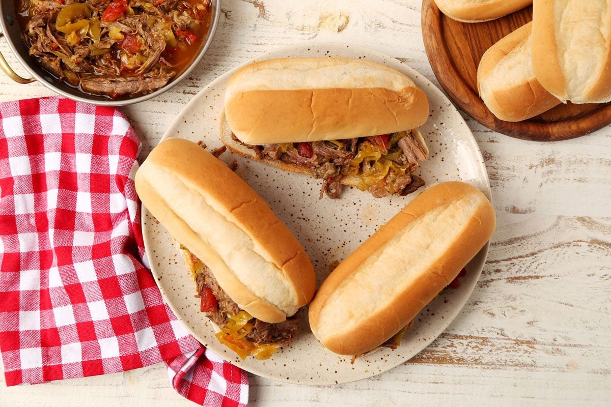 Close up of Taste of Home's Italian Beef Sandwiches served on a platter on a white wooden surface.