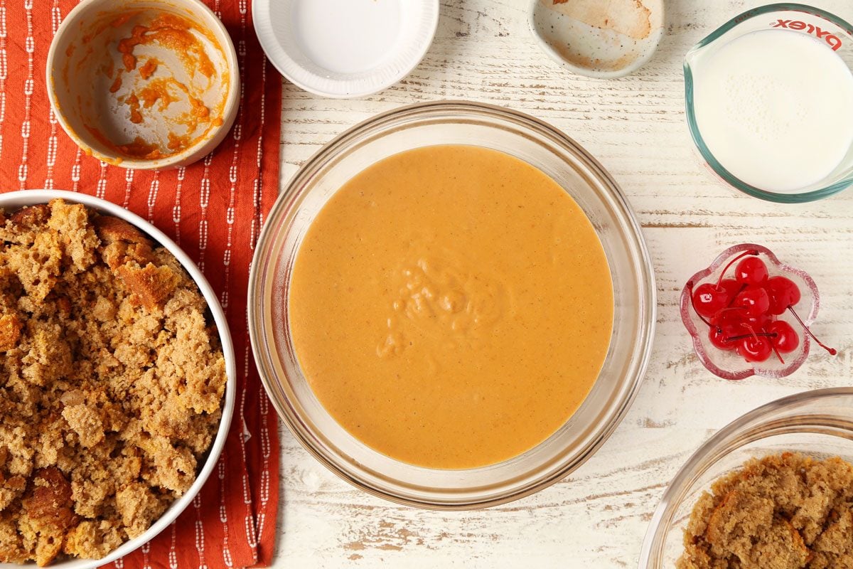 Process of making Taste of Home's Pumpkin Trifle layered in a glass serving bowl on a white wooden surface.