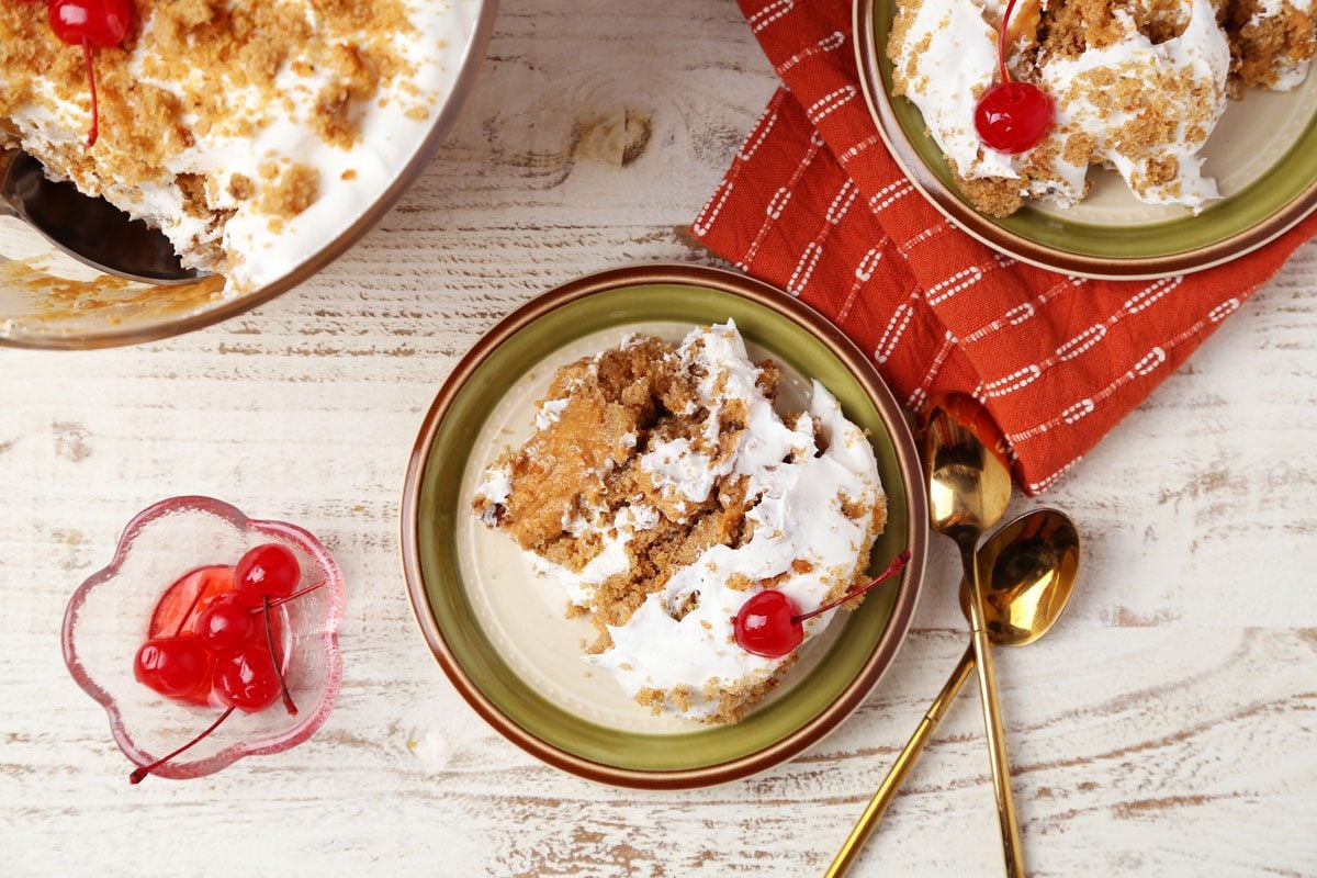 Close up of Taste of Home's Pumpkin Trifle layered in a glass serving bowl on a white wooden surface.