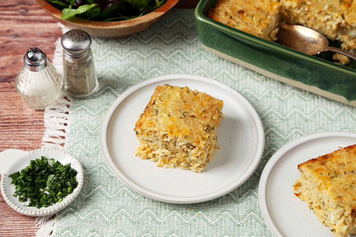 Close up of Taste of Home's Cheesy Rice Casserole in a green baking dish on a wooden surface.