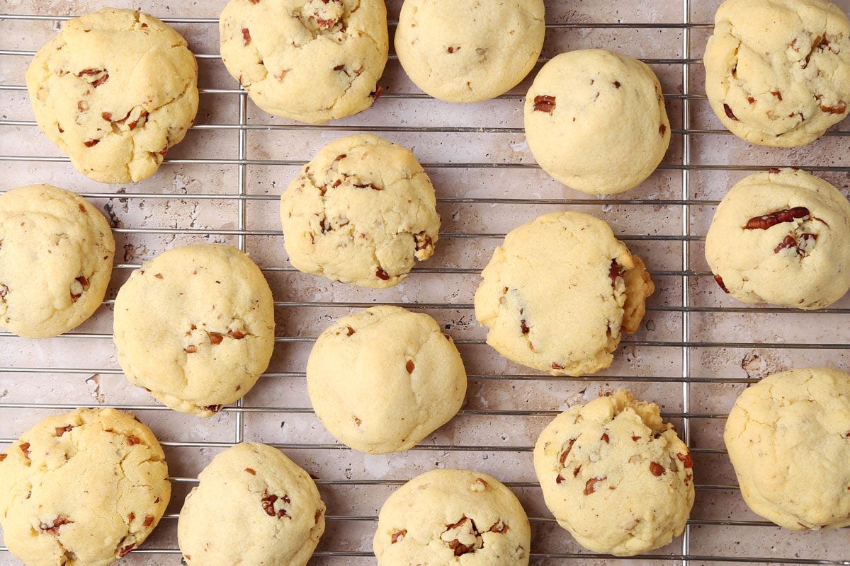 Taste of Home's Butterscotch Cookies on a wire rack with milk on the side and a small bowl of pecans.