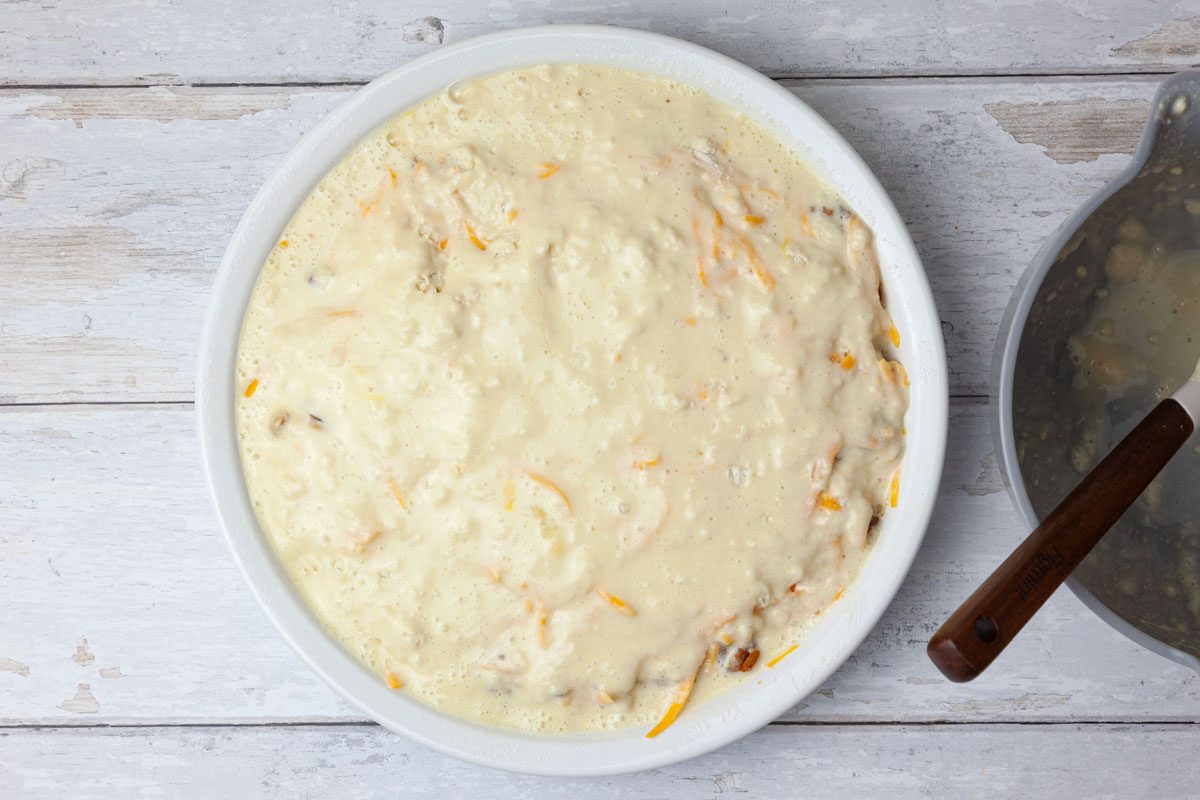 Step 4 of Taste of Home Taco Pie is to whisk together the eggs and milk. Add the biscuit mix and stir just until combined, making sure not to overmix. Pour this mixture evenly over the cheese layer on the pie plate.