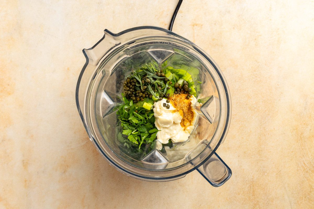 Taste of Home Vegan Potato Salad recipe photo of the green onions, avocados, parsley, mayonnaise, tarragon, capers and seasoned salt in a blender.