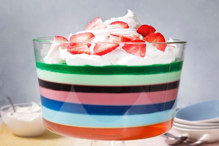 A layered dessert in a glass bowl, topped with whipped cream and strawberries