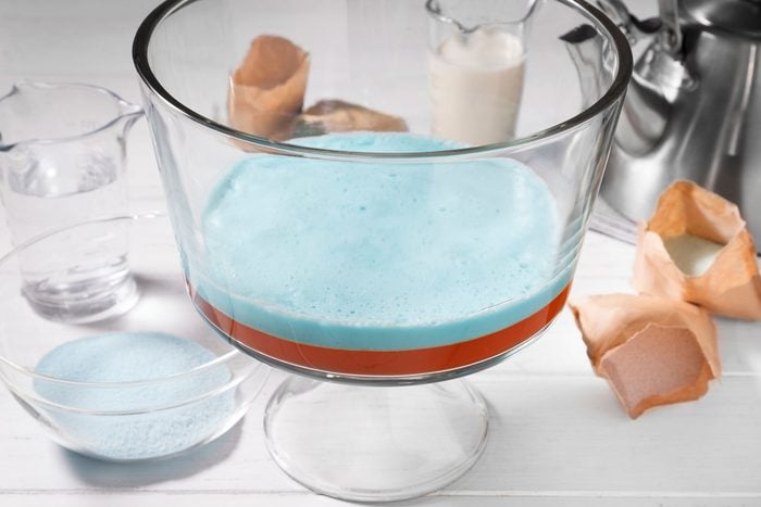 A large clear glass bowl with a light blue liquid inside it sits on a white table surface