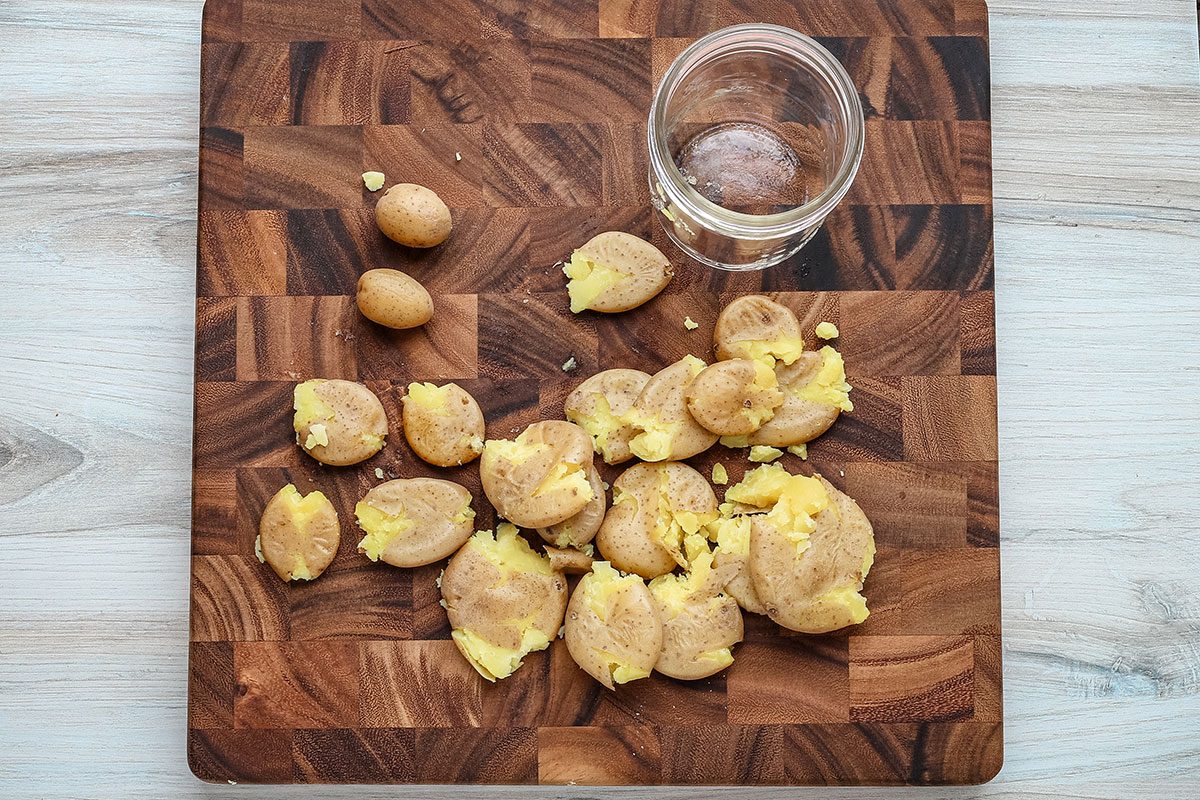 Air fryer smashed potato prep: flattening the potatoes with the bottom of a jar.