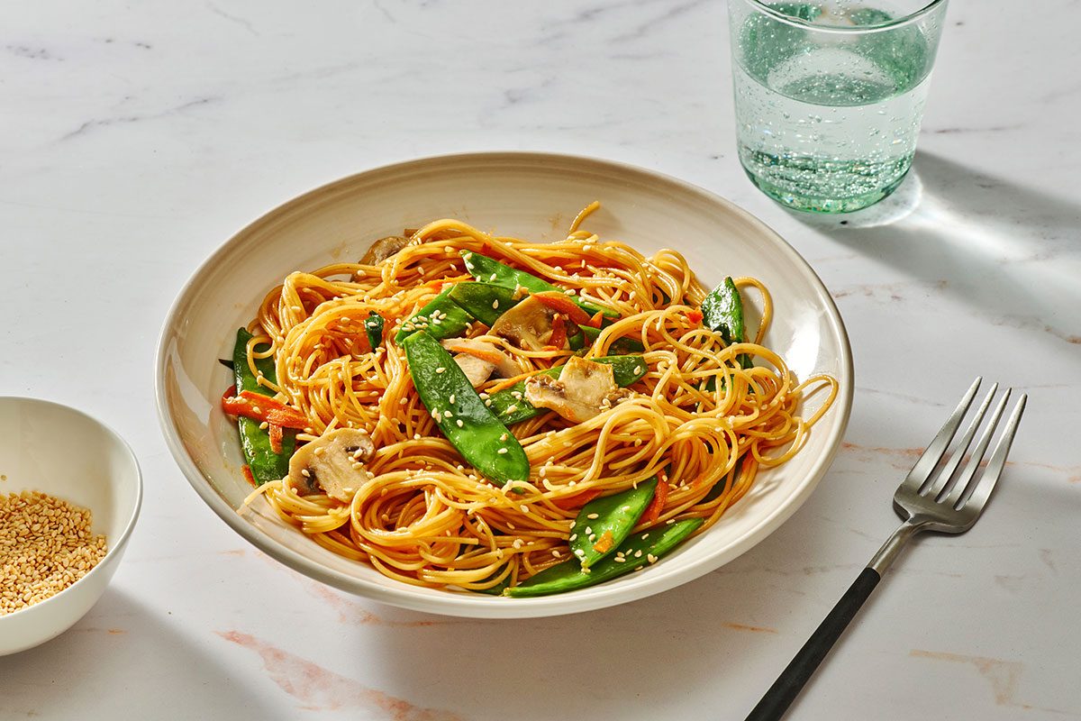 Asian spaghetti served in a bowl garnished with toasted sesame seeds