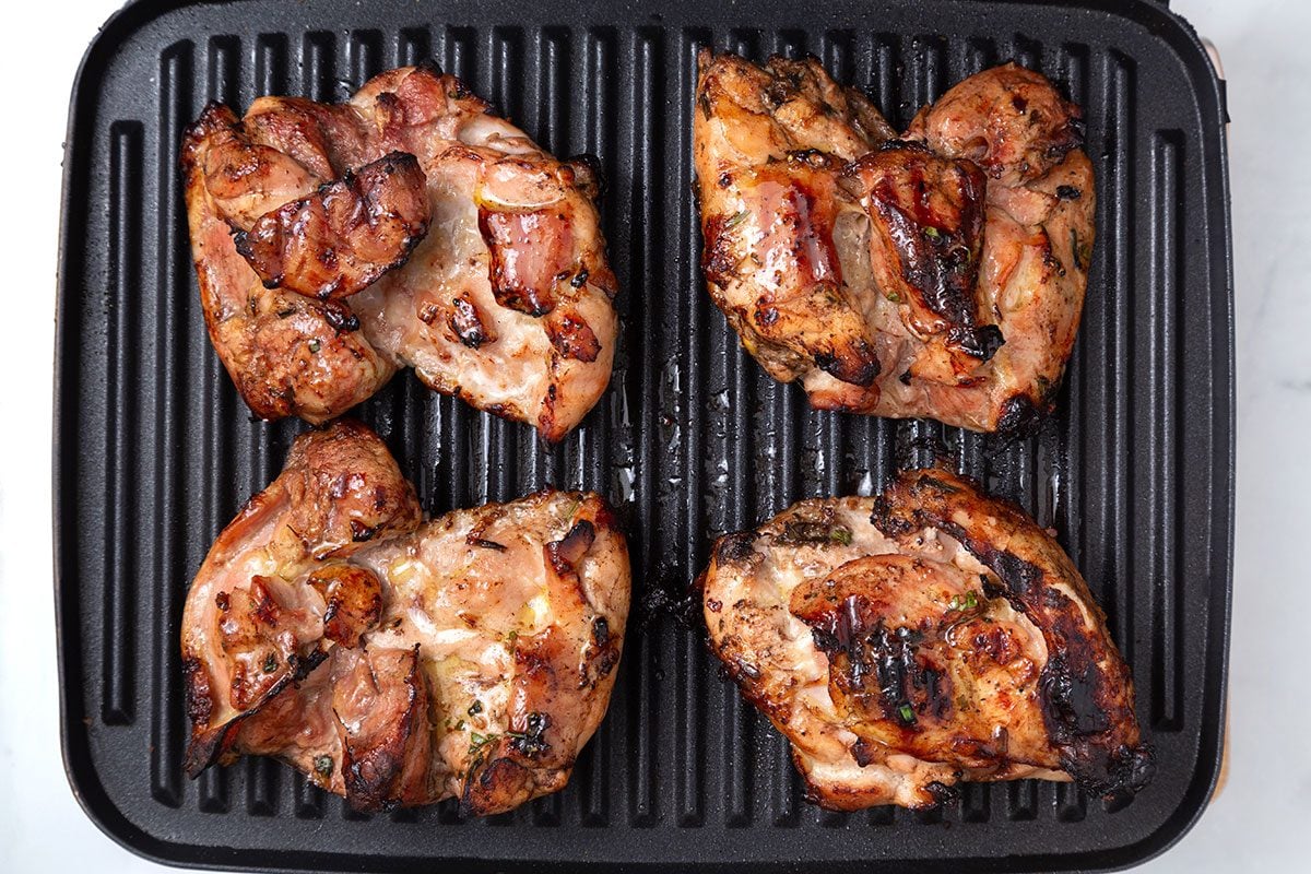 Marinated chicken thighs on a grill for step two of Balsamic Chicken recipe for Taste of Home