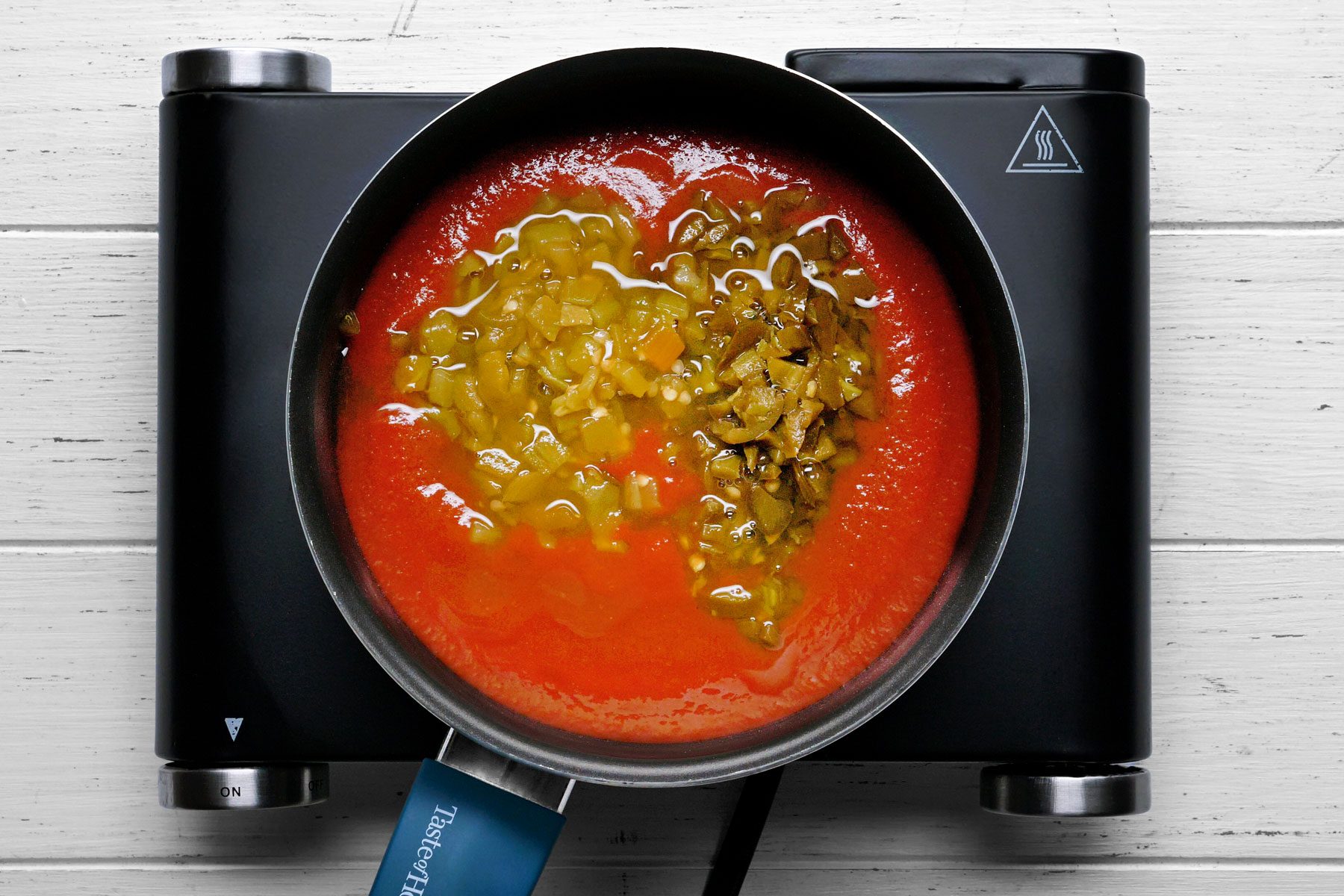 Green chiles, jalapenos and remaining tomato sauce combined in a saucepan.