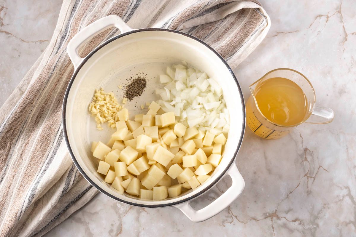 cooking Broccoli Cheddar Potato Soup in a white pot