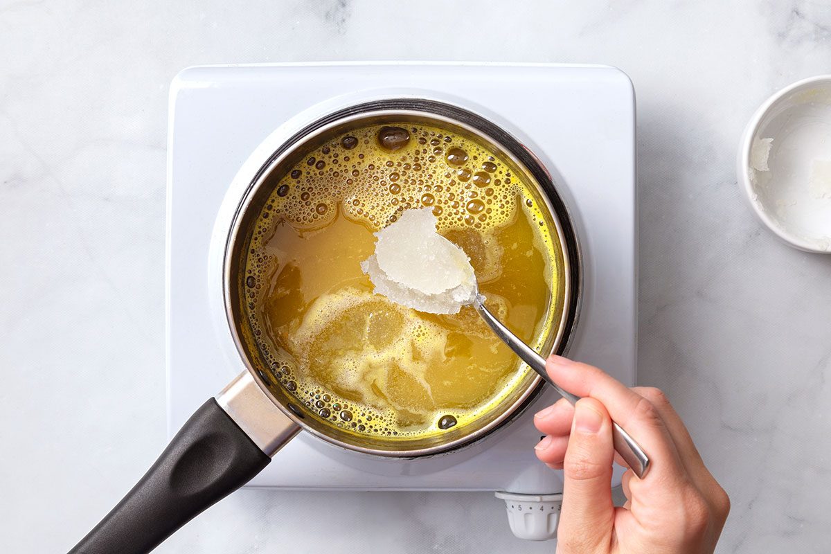 Unflavored gelatin being added to boiling pineapple juice in a saucepan for step two of Broken Glass Jello recipe for Taste of Home