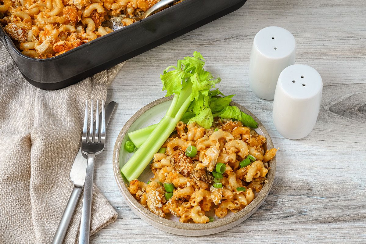 A serving of Buffalo chicken mac and cheese with fresh celery sticks on the side.