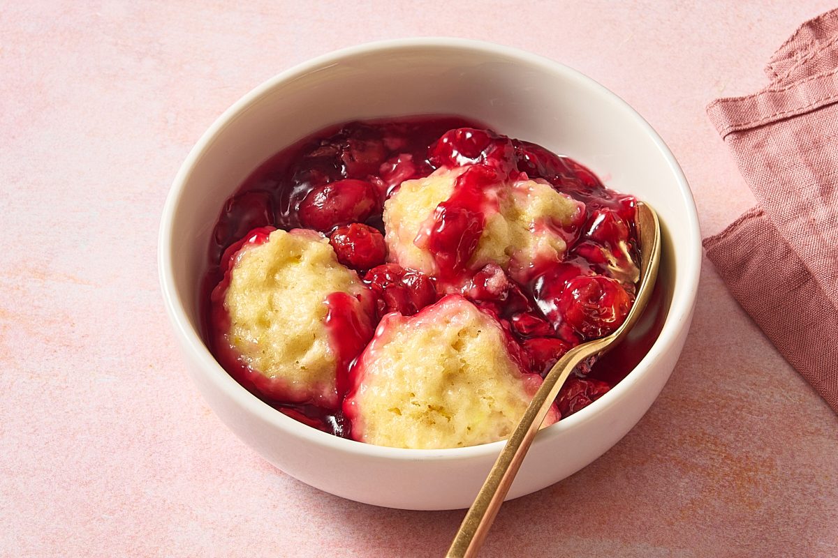 Angled shot of a bowl of cherry dumplings with a spoon