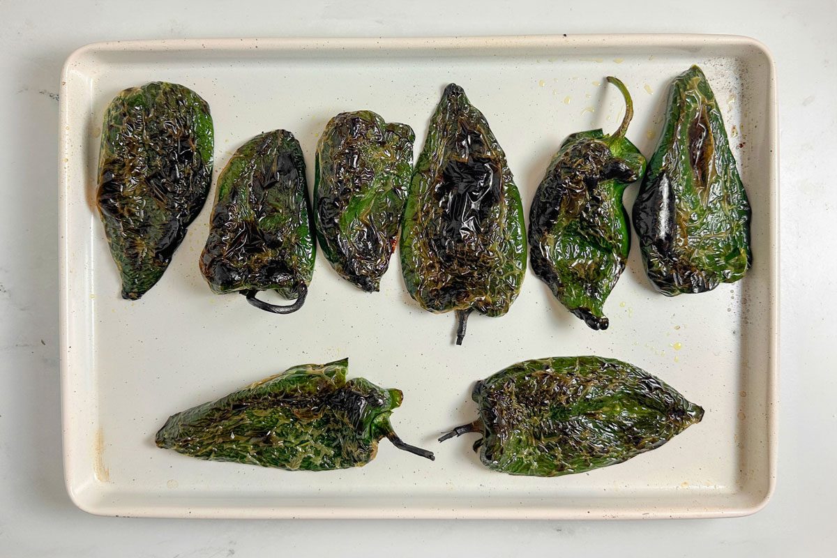 Blistered poblano peppers for Taste of Home Chili Stuffed Poblano Peppers on a white baking sheet
