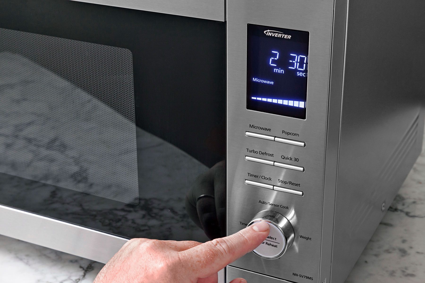 A hand can be seen adjusting microwave settings.