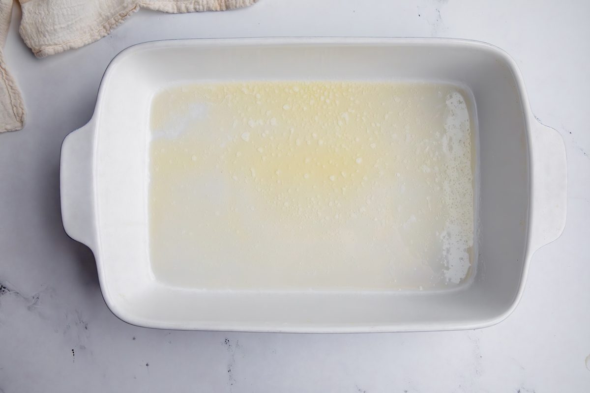Overhead shot for Taste of Home Cornflake Chicken, melted butter in a large baking dish.