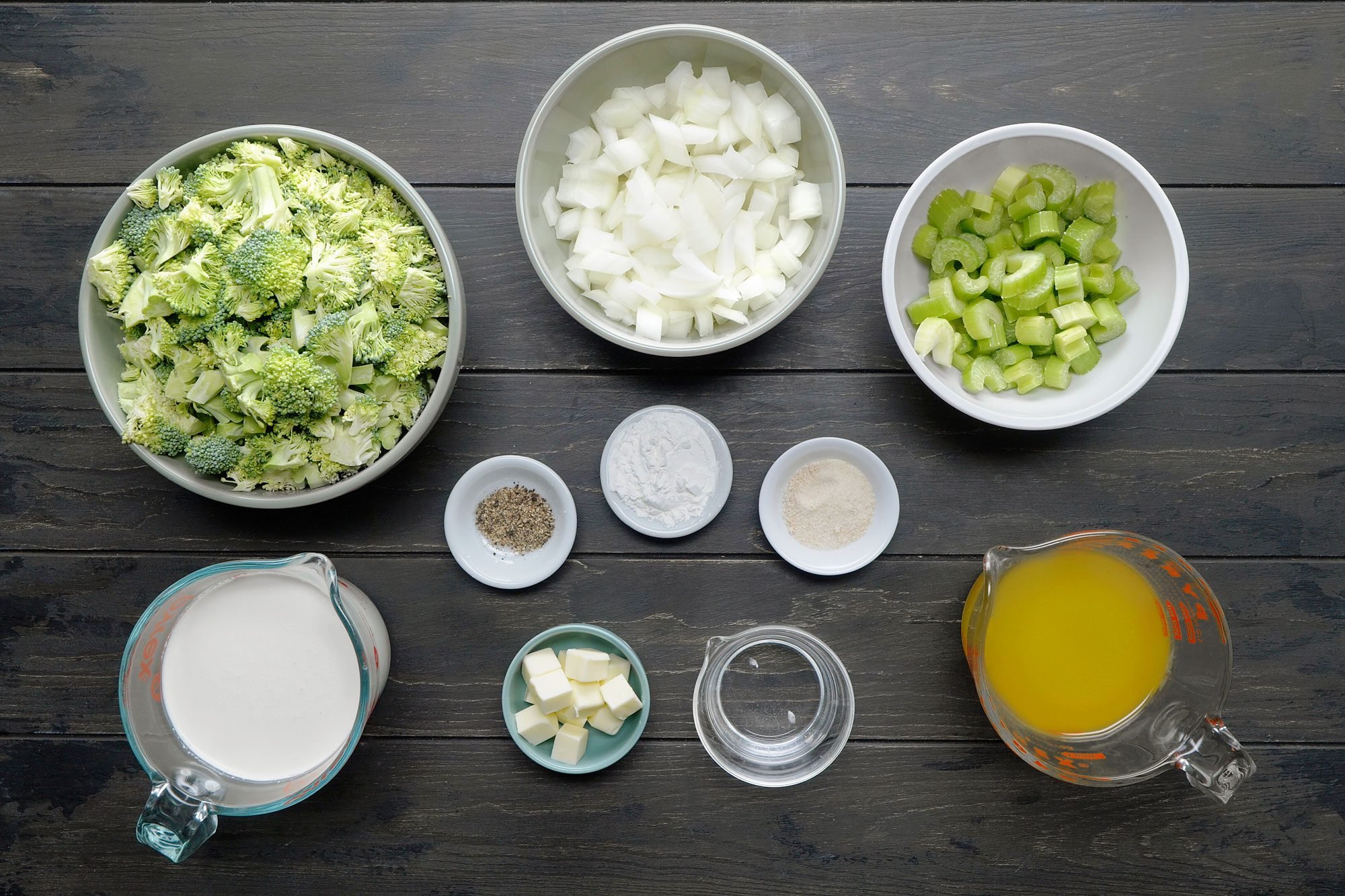 overhead shot of Cream of Broccoli Soup ingredients placed over black wooden background;