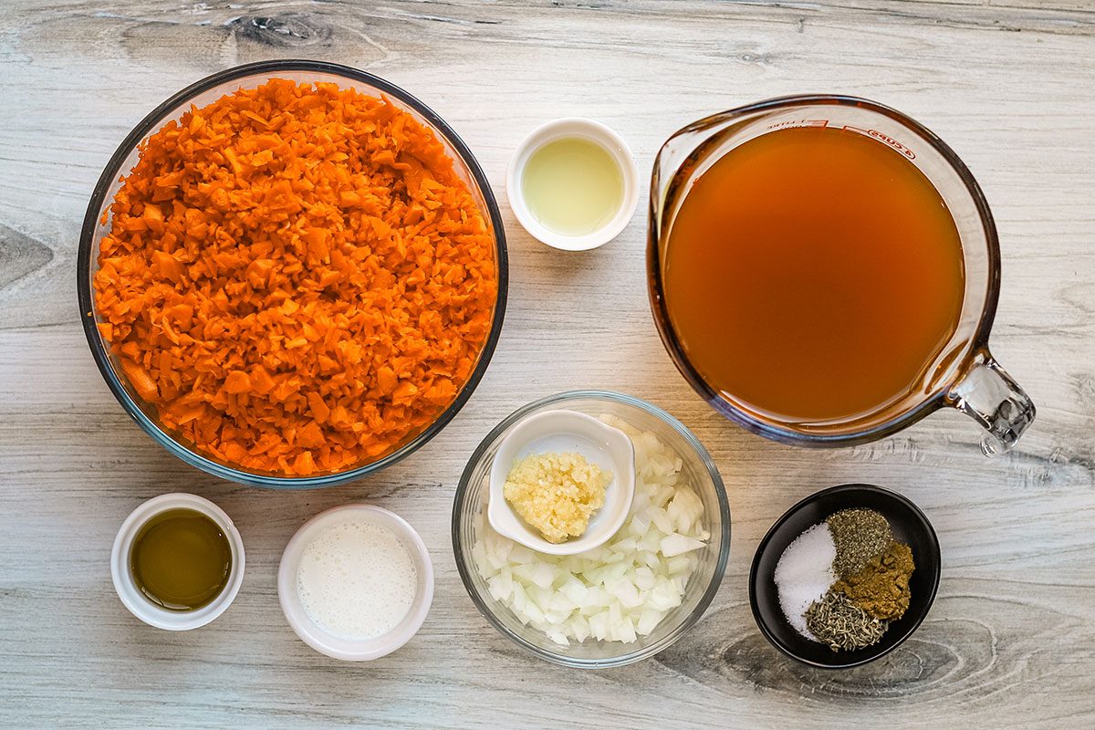 Ingredients for carrot soup with onions, garlic, seasonings, cream, vegetable broth and lemon juice.