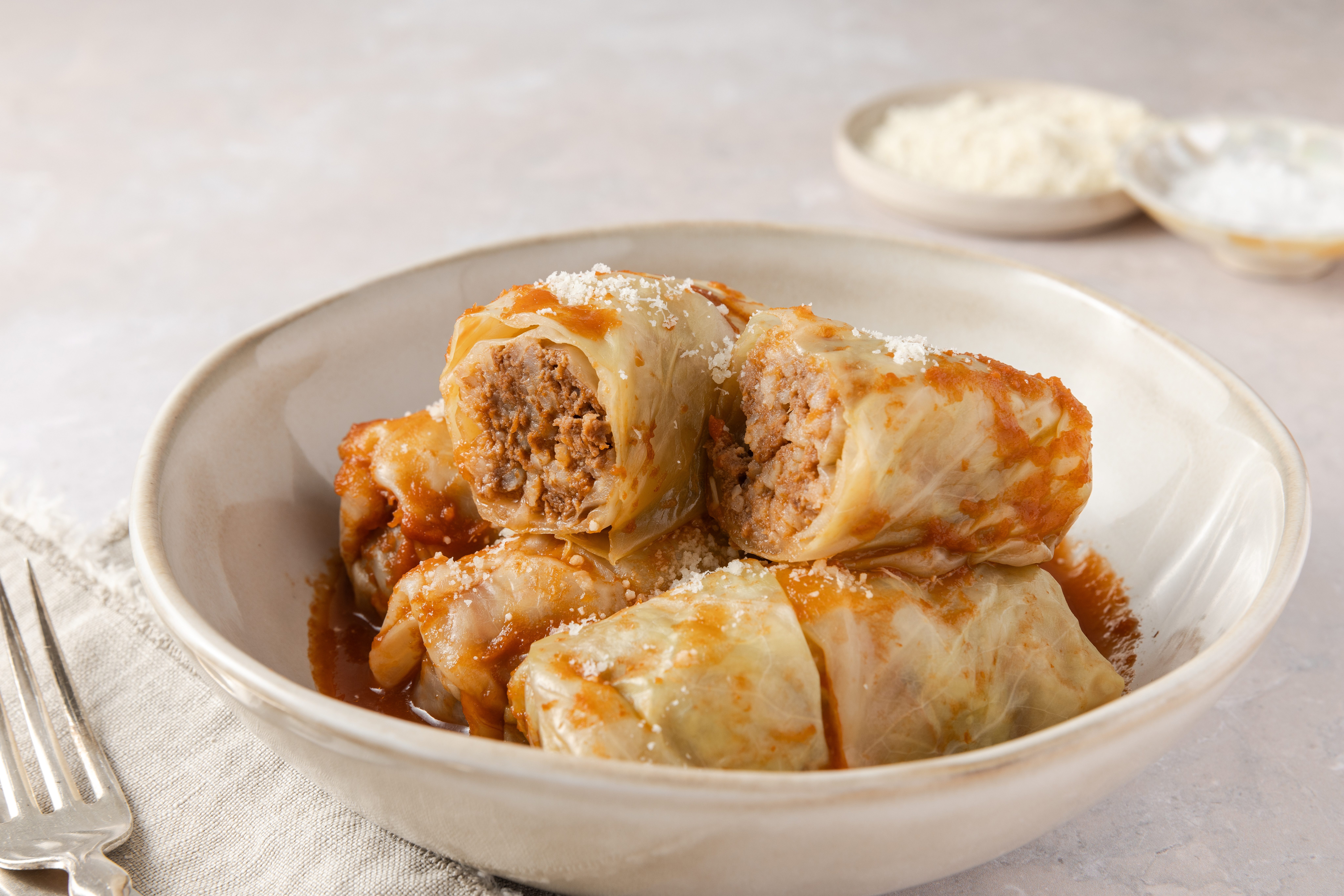 Cabbage rolls served in bowl topped with parmesan cheese.