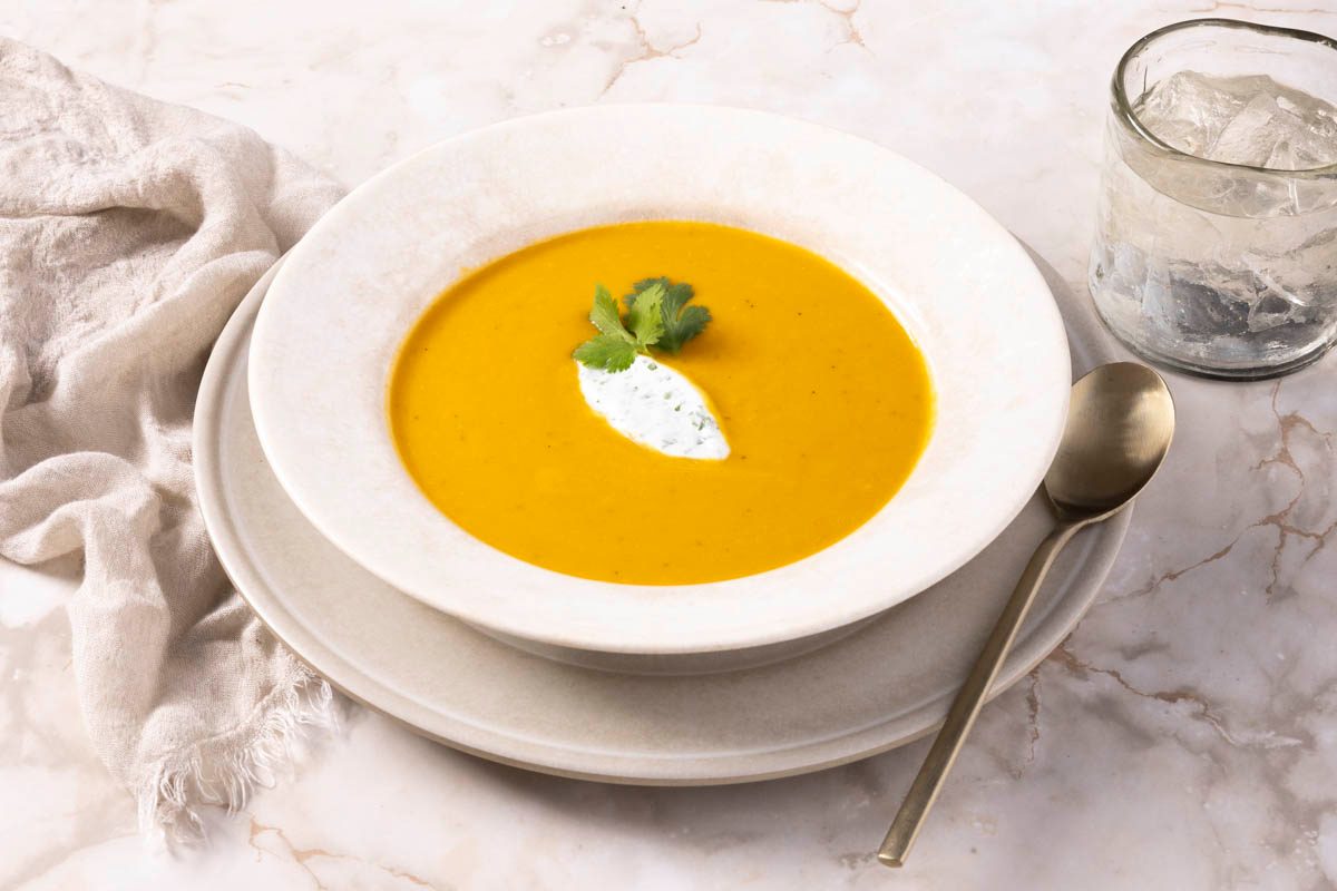 Curried Butternut Squash Soup in a white bowl 3/4 view on marble table