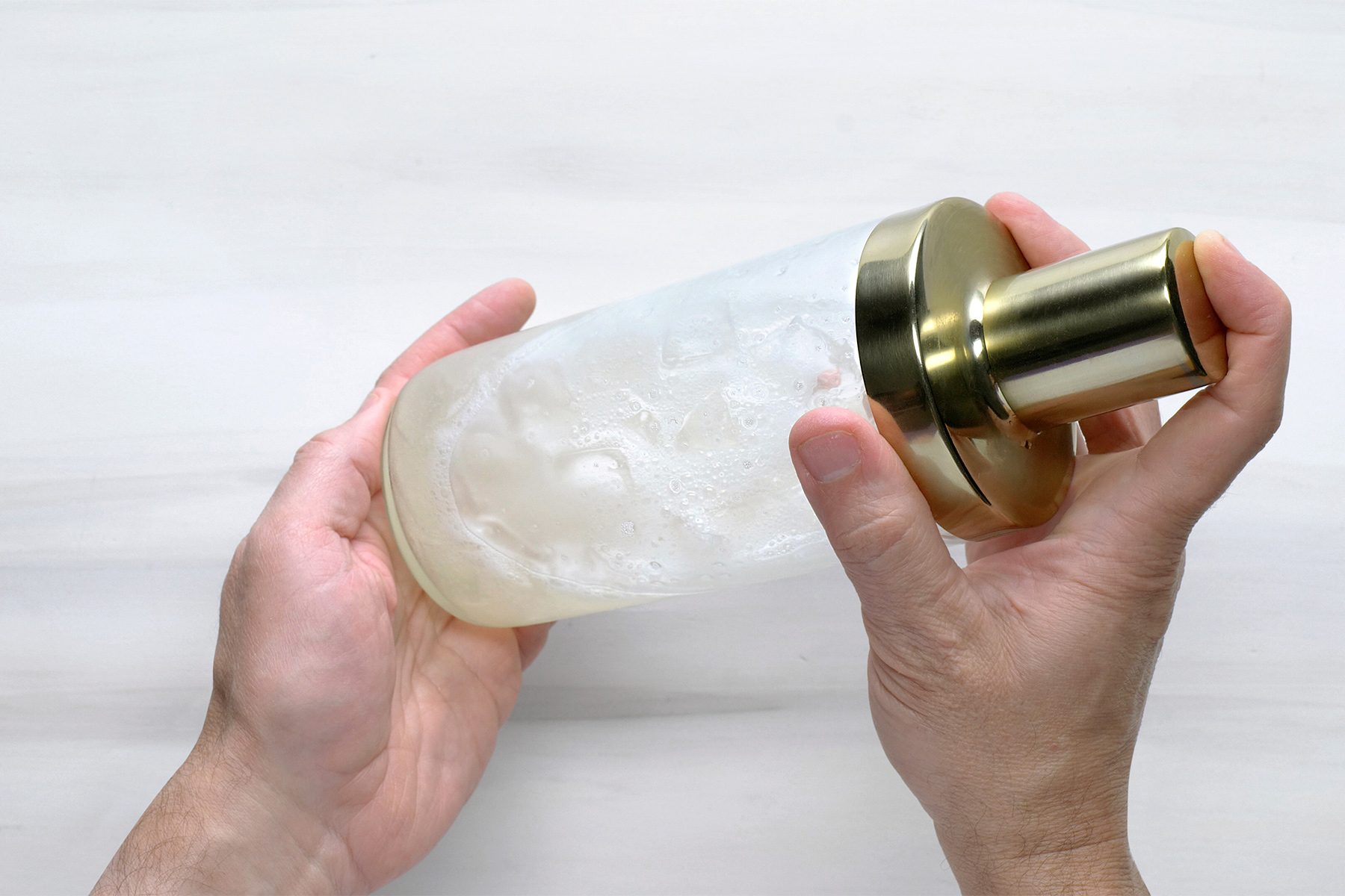 Overhead shot of cover shaker and shake; until condensation forms on outside of shaker; white background;