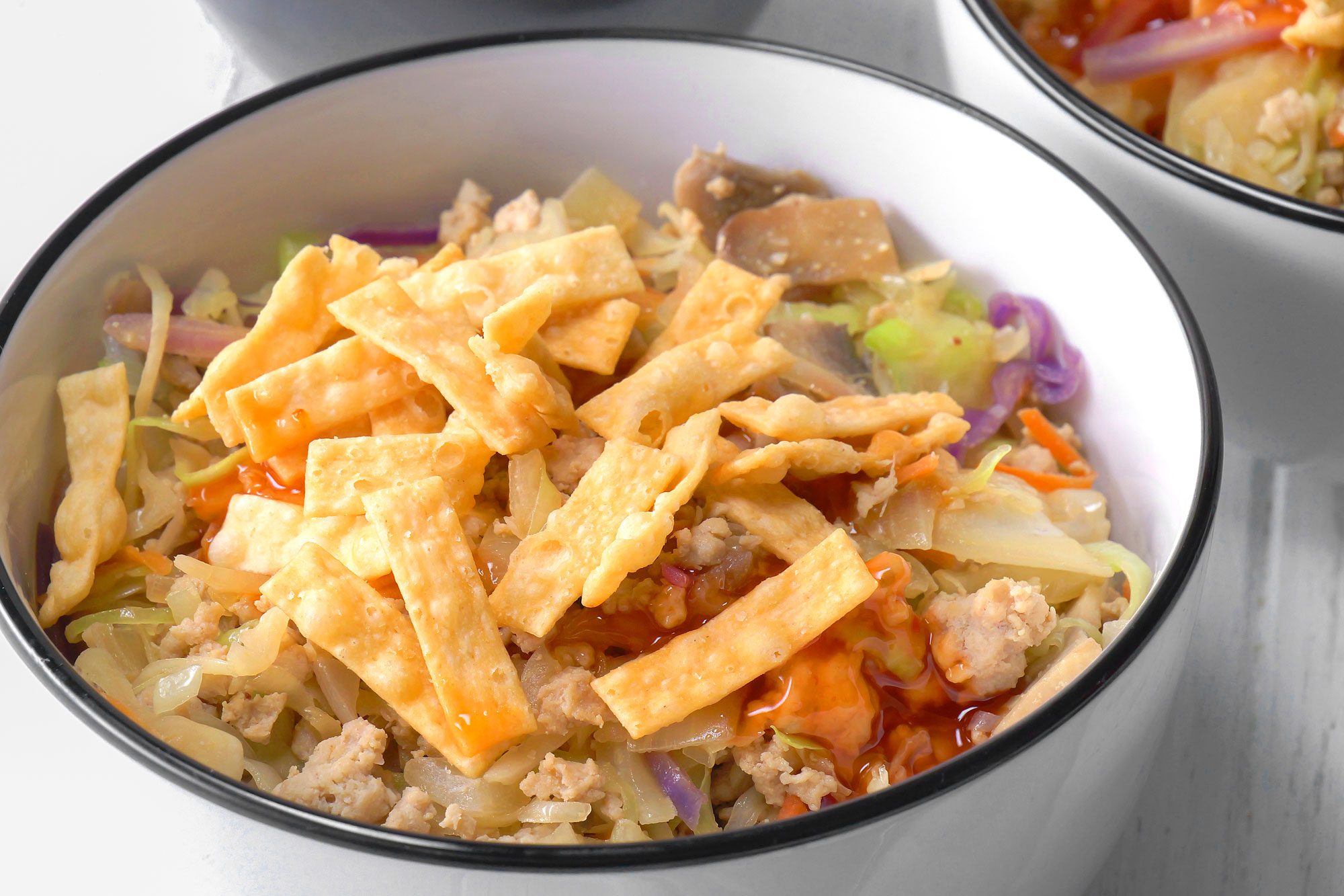 Egg Roll in a Bowl, a popular Chinese-inspired dish, A white bowl is filled with a vibrant mixture of shredded cabbage, chopped mushrooms, and ground chicken, all tossed in a sweet and tangy sauce