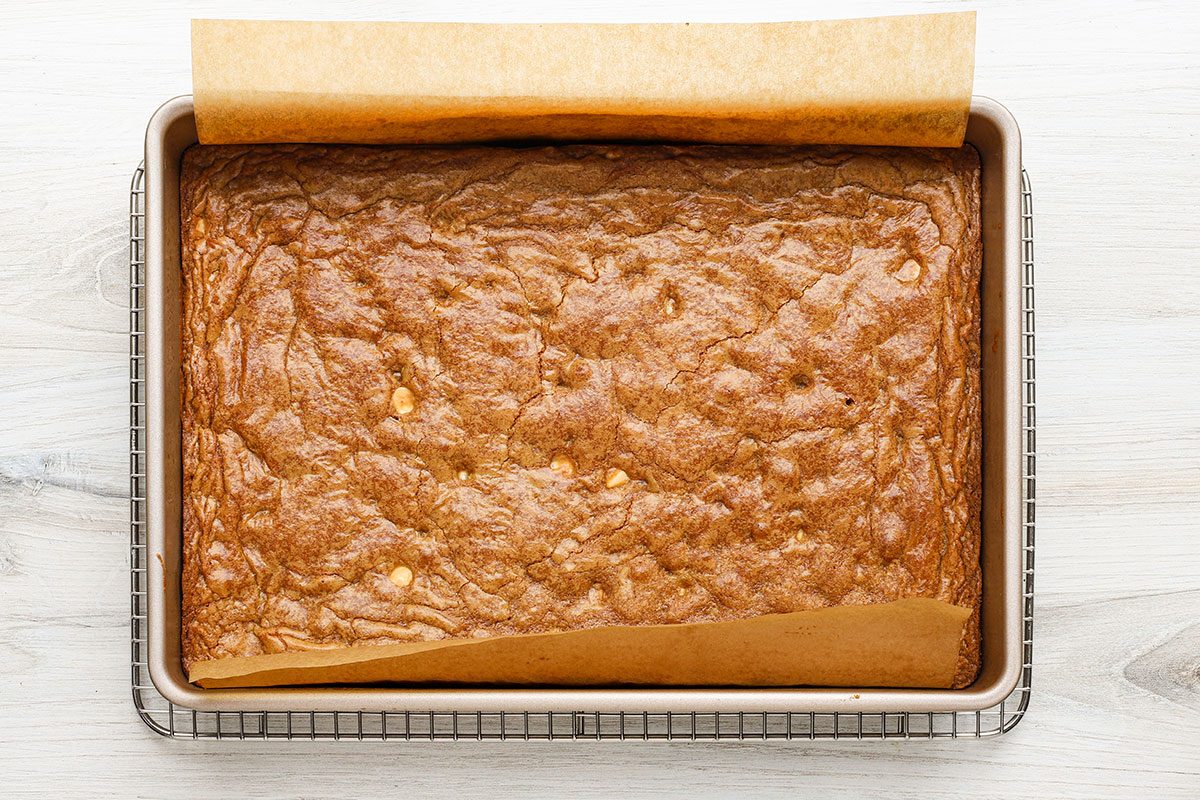 Baked gingerbread blondies with white chocolate chips, cooling on a rack.