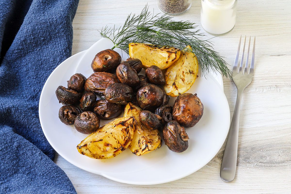 Grilled mushrooms and lemon wedges with a dill garnish.