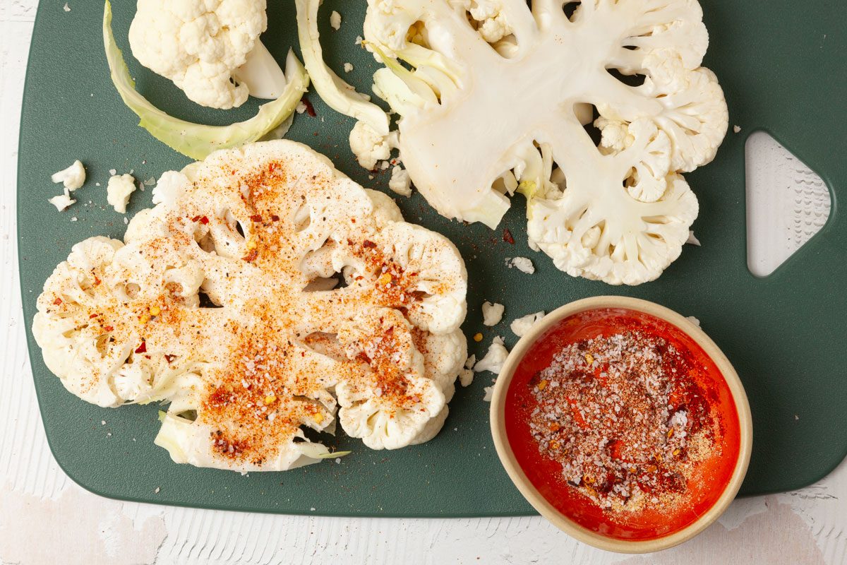 Step 2 of Taste of Home Grilled Cauliflower Steaks is to combine the salt, garlic powder, smoked paprika, pepper and red pepper flakes; sprinkle over cauliflower. Grill the cauliflower over direct heat for two to three minutes on each side. Move to indirect heat and cover. Cook them until tender and edges are lightly browned, 15 to 20 minutes, turning once halfway through cooking.