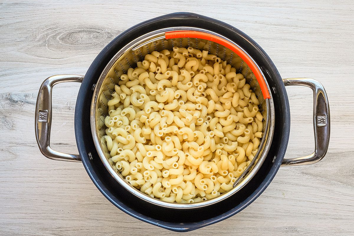 Draining the macaroni pasta for jalapeno mac and cheese, a recipe from Taste of Home..
