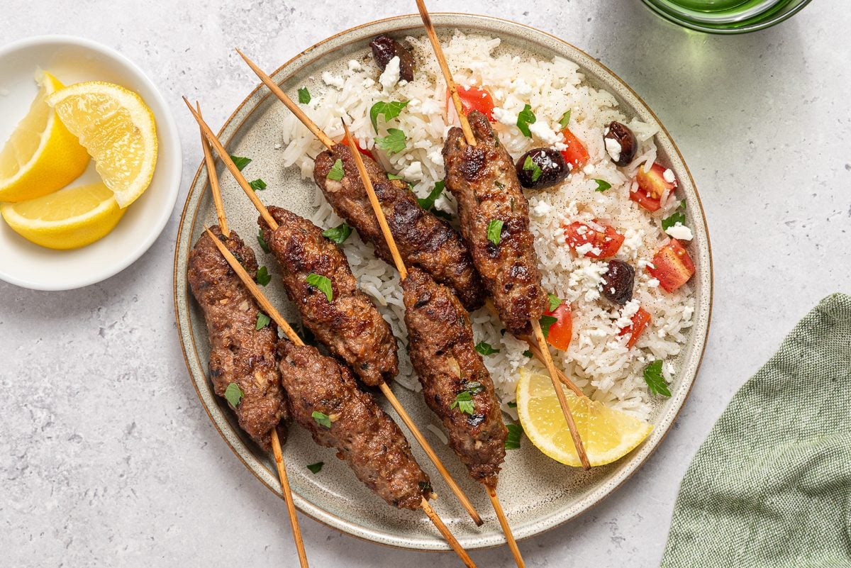 Kofta Kabob Served With Rise, Olives, Tomatoes, Feta And Lemon