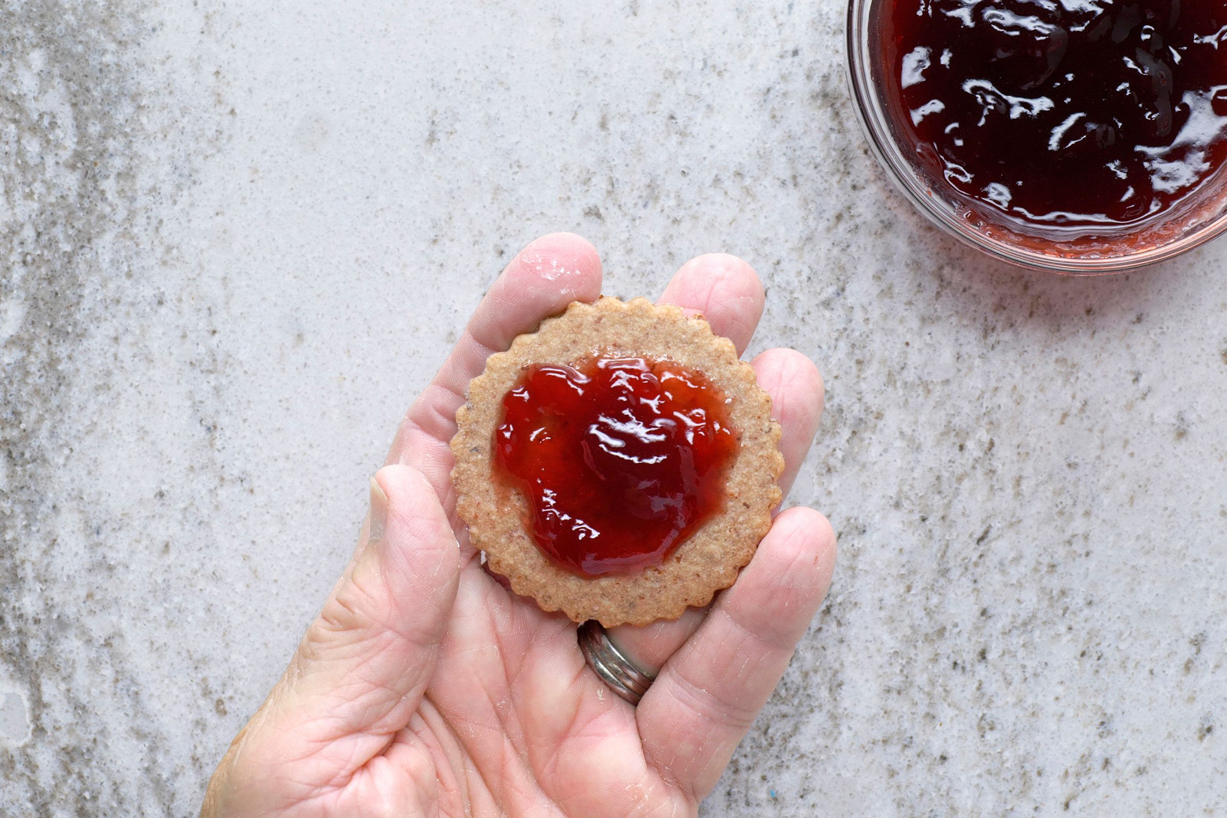 Spreading bottom of cookie with half teaspoon of jam