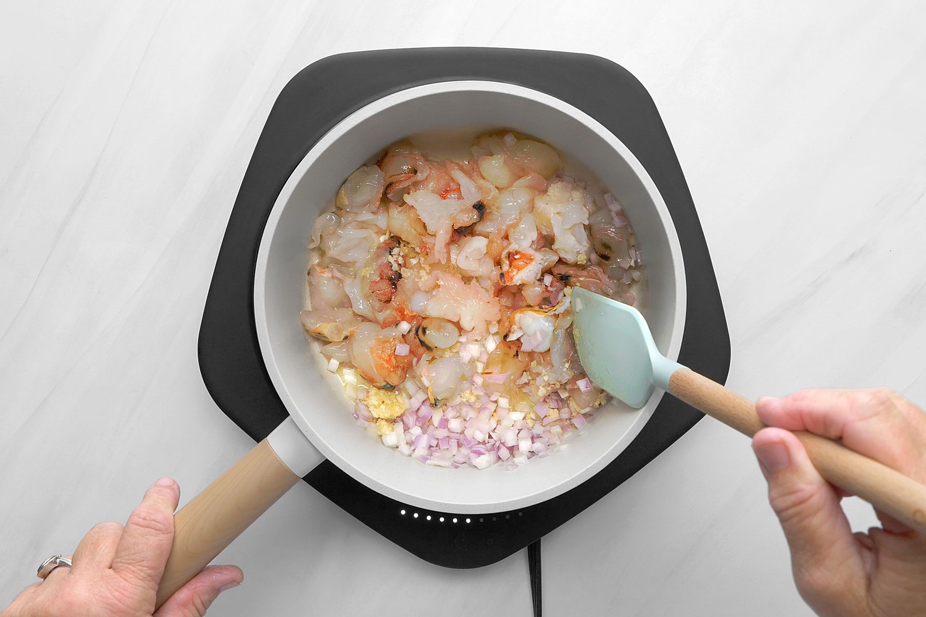 Chopped lobster, shallot and garlic heating in a large saucepan.