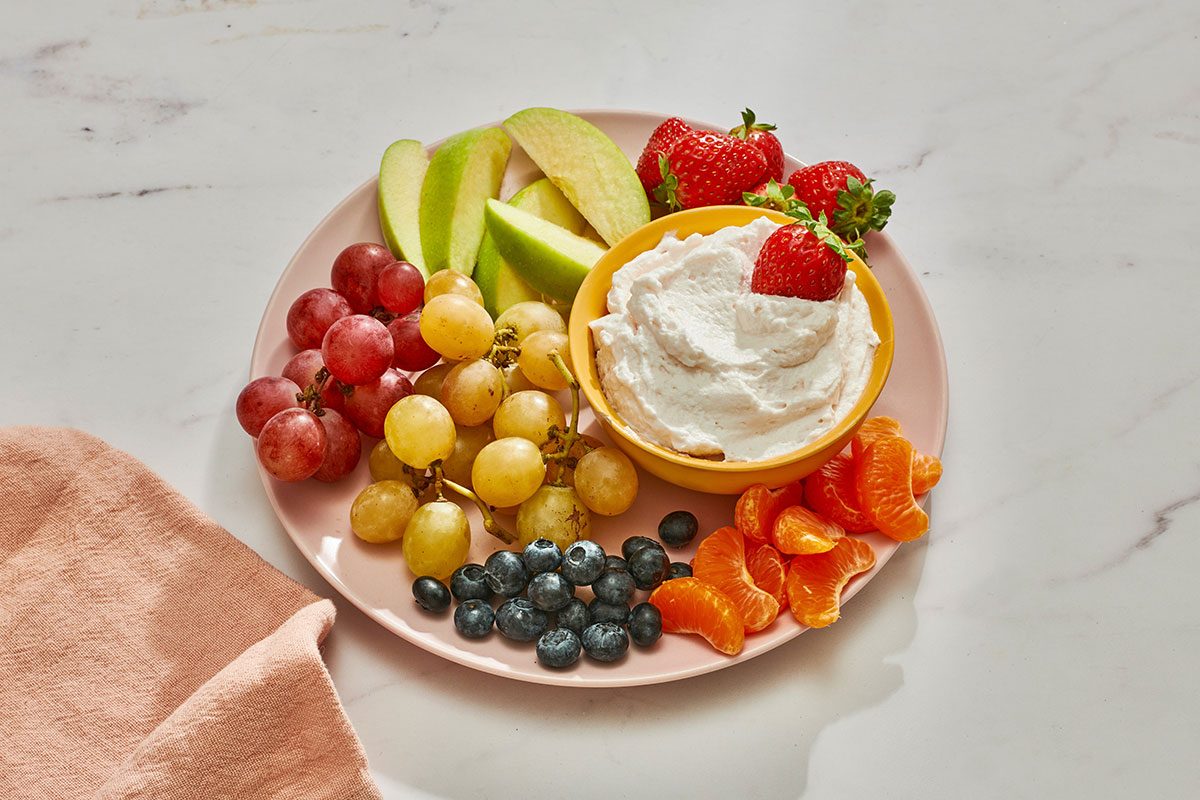 Marshmallow fruit dip in a bowl on a platter served with fresh fruits