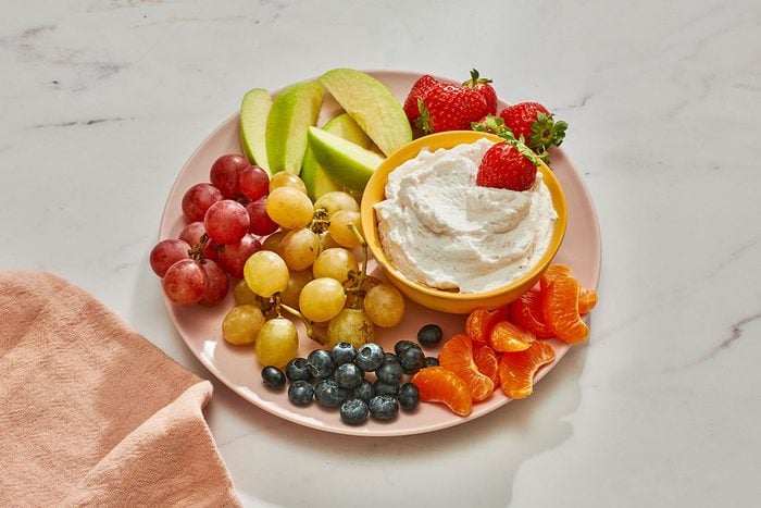 Marshmallow fruit dip in a bowl on a platter served with fresh fruits