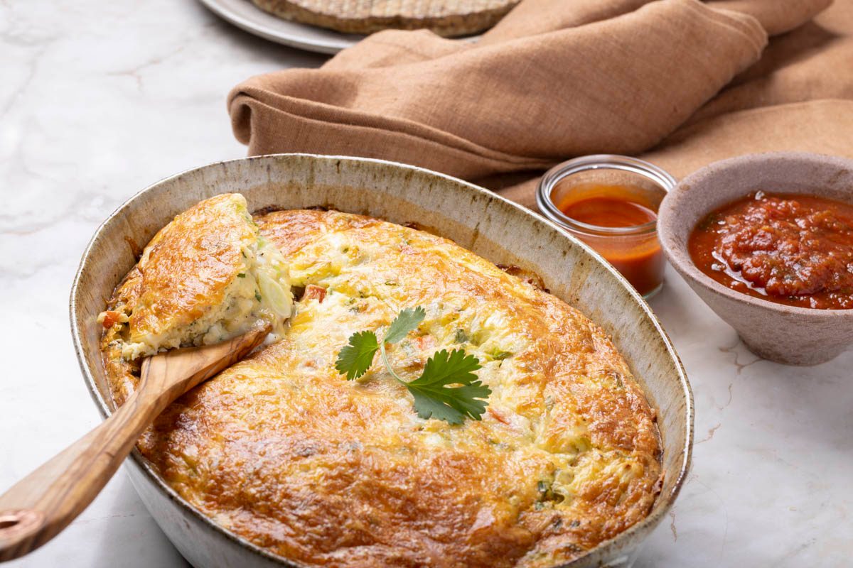 Mexican Breakfast Casserole in a baking dish with wooden spoon on marble table