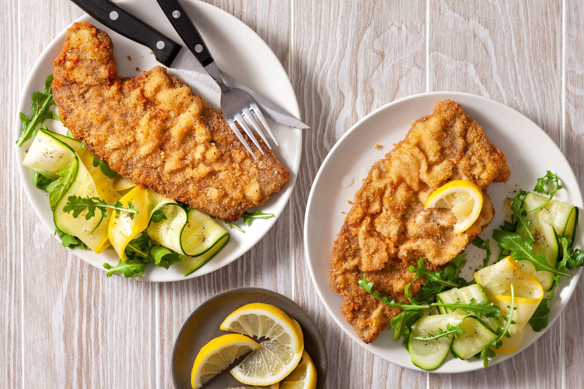 overhead shot of steak milanesa with lemon wedges