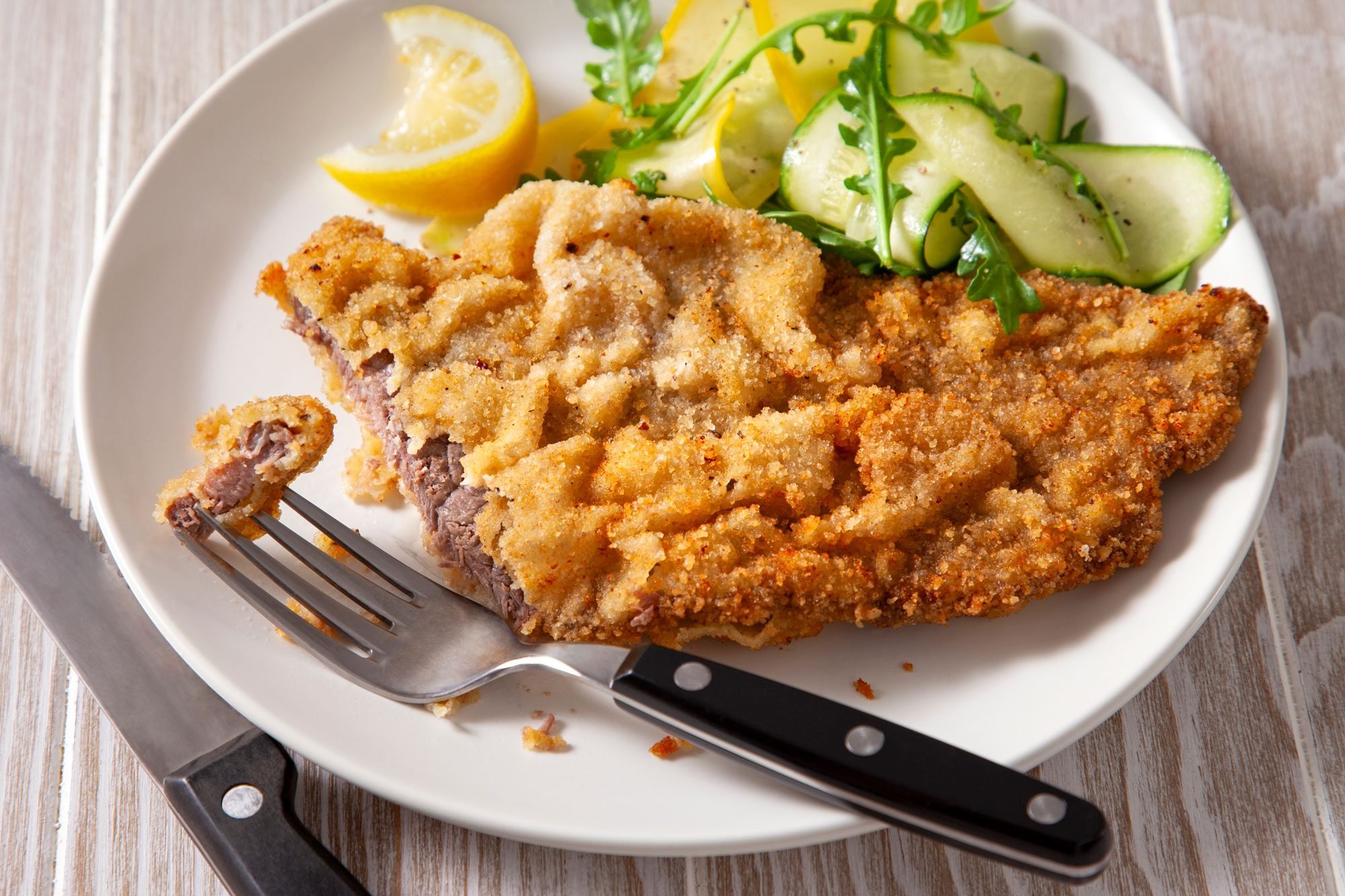 3/4th shot of steak milanesa with lemon wedges