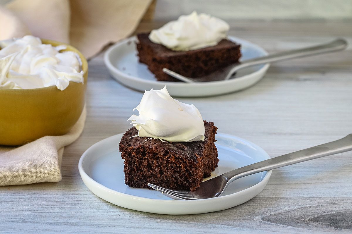Old fashioned molasses cake servings on plates with whipped topping.