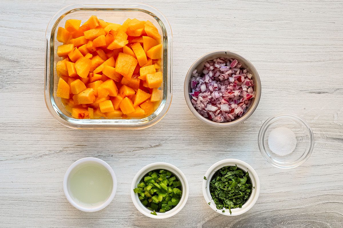 Ingredients for peach salsa, including red onion, cilantro, jalapeno pepper, chopped peaches, lime juice and salt.